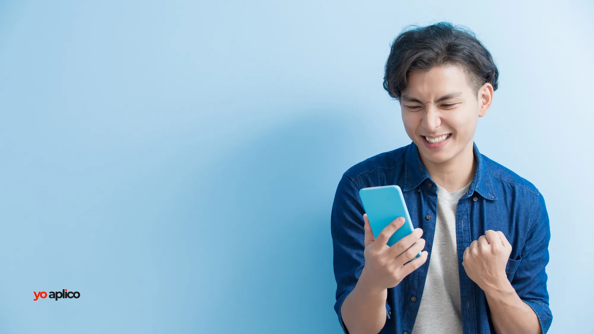 Un joven mira su celular, se ríe y cierra el puño.